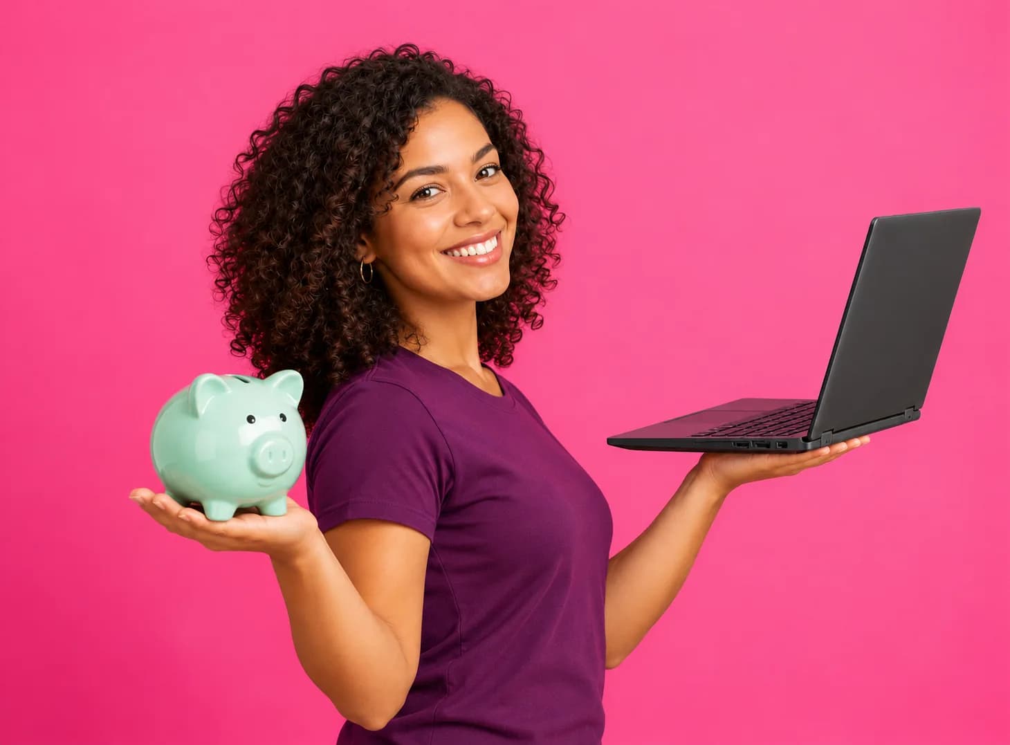 A woman holding a piggy bank in one hand and a laptop in the other